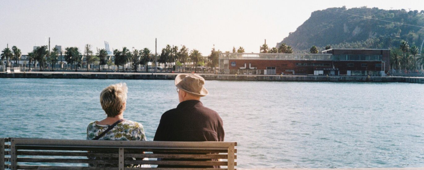 An elderly couple enjoys a peaceful moment by the waterfront in Barcelona.