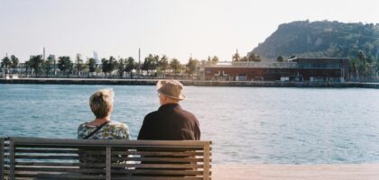 An elderly couple enjoys a peaceful moment by the waterfront in Barcelona.