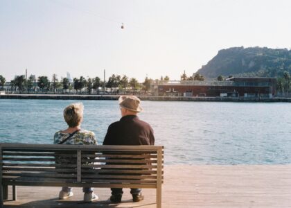 An elderly couple enjoys a peaceful moment by the waterfront in Barcelona.