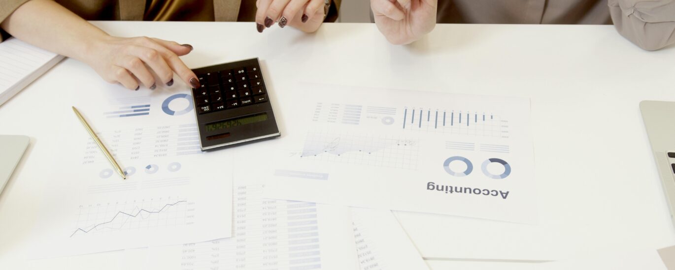 Two professionals analyzing financial documents with a calculator.