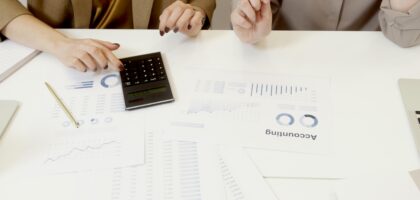 Two professionals analyzing financial documents with a calculator.
