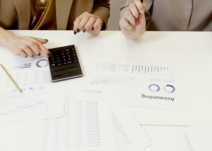 Two professionals analyzing financial documents with a calculator.